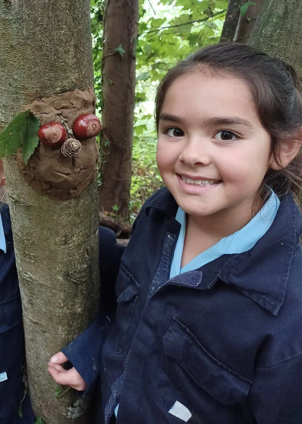 Sherborne Prep student smiling next to forest school sculpture.