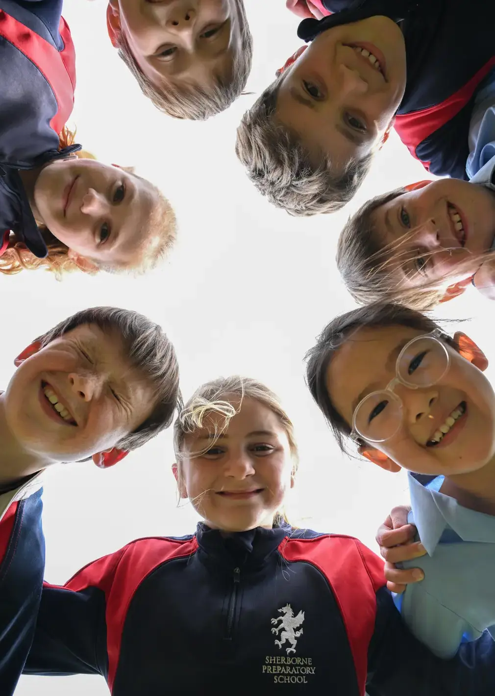 Students in huddle smiling down at camera