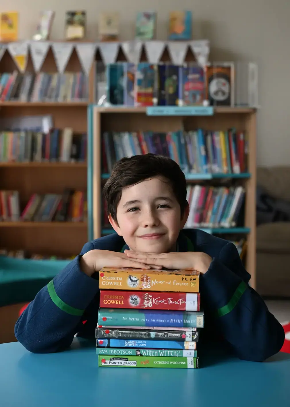 Boys Posing Resting His hands and His Head on a Stack of Books in Class