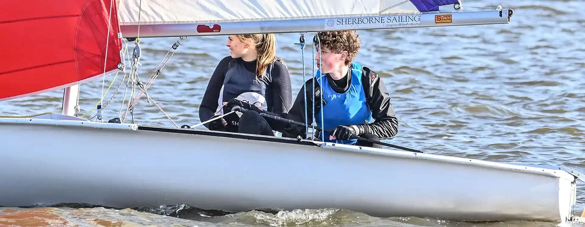 Male and Female Students Sailing in Boat