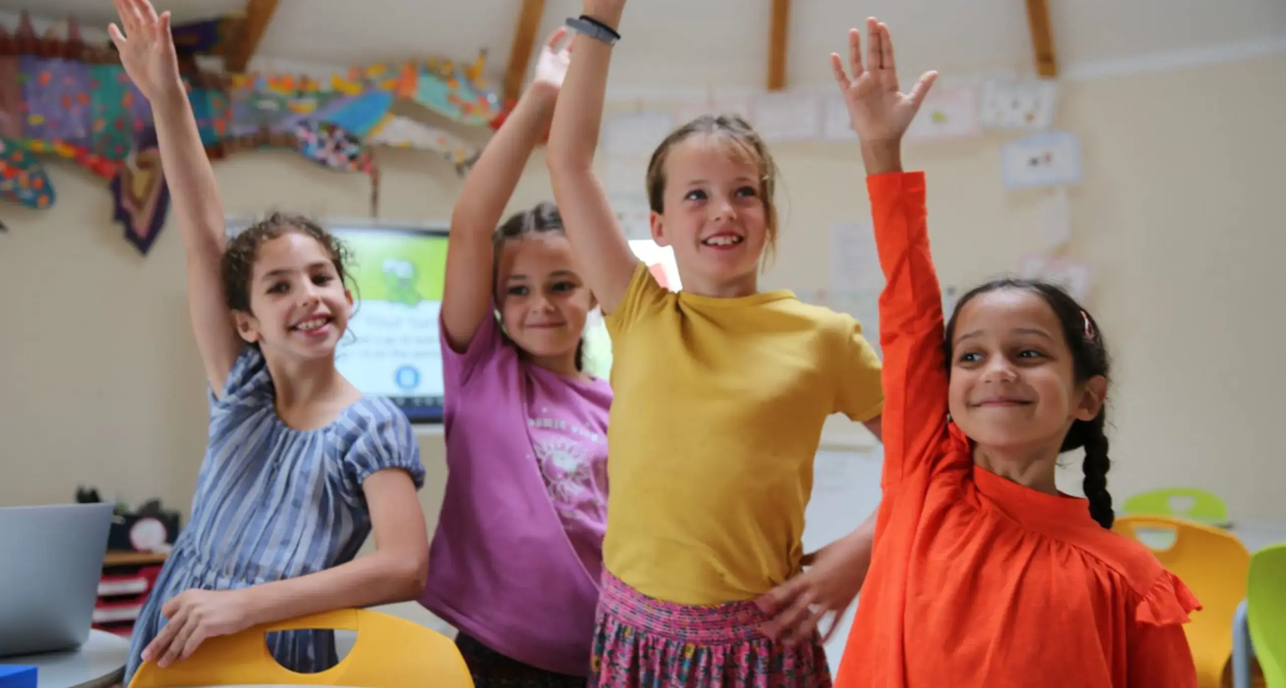 Students Raising Hands and Smiling While Wearing Bright Colors